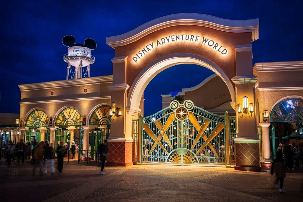 Entrée de Disney Adventure World à Disneyland® Paris, avec son portail illuminé de nuit.