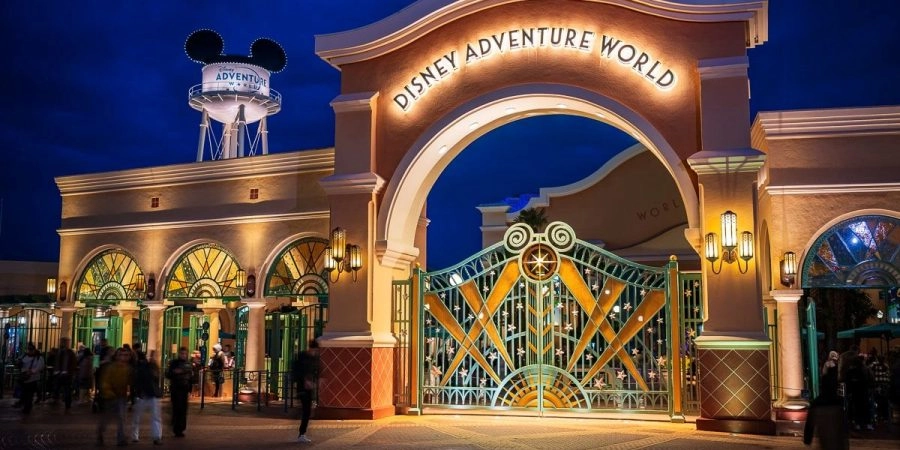 Entrée de Disney Adventure World à Disneyland® Paris, avec son portail illuminé de nuit.